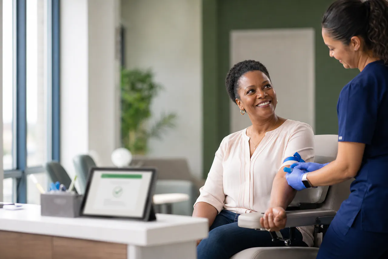 Patient receiving a blood draw at a modern lab with digital order confirmation